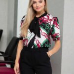 Model wearing a multicolor chain print blouse featuring a stylish bow-front tie, square neckline, and a regular fit, paired with casual bottoms.