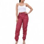 alt text for this item? A model wears high-waist, skinny-fit red plaid windbreaker joggers. The pants have a drawstring waist and shirring details at the ankles, which creates a jogger silhouette.