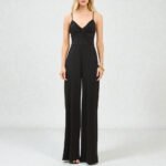 Woman wearing a sleeveless V-neck palazzo slip jumpsuit with a twisted waist detail and floor-length flared legs.