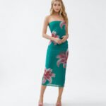 Model wearing a strapless tube midi dress in a vibrant Marina Teal Lily floral print, featuring a bodycon fit, power mesh fabric, and a stylish back slit detail.
