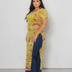 A plus-size short-sleeve top featuring a vibrant abstract geometric print in radiant yellow and multicolor. The blouse is crafted from a sheer power mesh fabric and features a classic round neck and clean side slits at the hem.