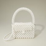 A mini structured box handbag fully embellished with polished white pearl beads. The handbag features a fixed pearl top handle, a secure front flap closure, and a detachable rhodium-tone crossbody strap.