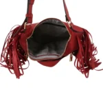 Top-down view into the open main compartment of a red fringe handbag, displaying a black and white chevron patterned lining.