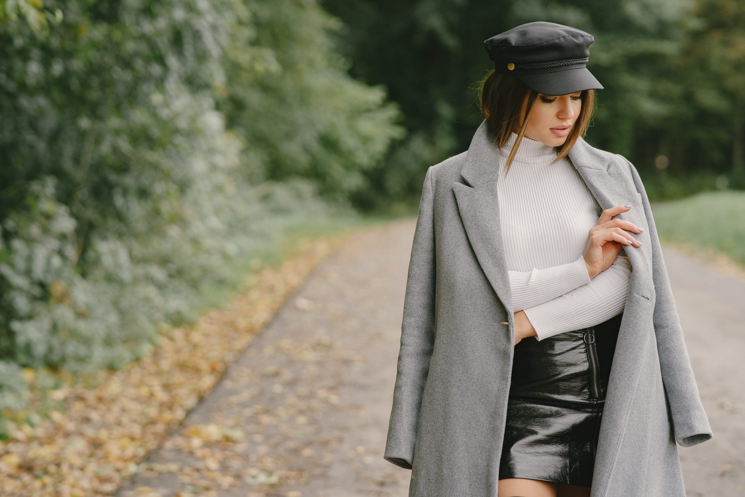 Winter Fashion On A Budget: Stay Cozy And Stylish Without Breaking The Bank 1 Stylish Brunette Woman In A Gray Coat And Black Cap Walking Outdoors, Showcasing Chic Winter Fashion.