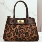 Leopard print patent leather small shoulder bag with a half-moon shape and zipper closure.