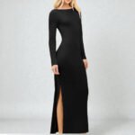 Woman wearing a black long sleeve bodycon maxi dress with a boat neck and side slit detail.
