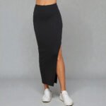 Full-length black solid maxi skirt with a chic side slit, featuring a smooth form-fitting knit fabric and high-waisted silhouette.